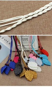 Detail of woven waist cord featuring layered leaf pendants and polished wooden beads