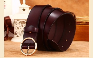 Detail of genuine dark brown leather belt featuring a polished round gold buckle and smooth texture