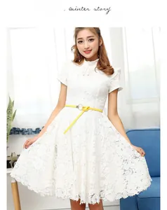 Détail d'une robe en dentelle blanche à manches courtes avec col montant et bouton perle