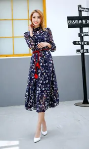 Detail of blue floral dress featuring a woven belt with red tassel accents
