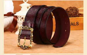 Détail d'une ceinture en cuir bordeaux gaufré avec une boucle fleurie rétro