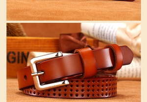 Detail of red-brown hollow leather belt with silver pin buckle and retro textures