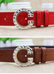 Detail view of rhinestone-encrusted G-buckle belts with crocodile pattern in red and brown