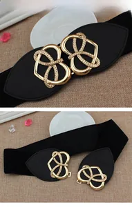 Detail of gold heart interlocking buckle with black elastic belt on textured background
