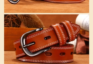 Macro shot of brown leather belt with white stitching and gunmetal needle buckle detail