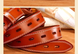 Macro shot of brown leather belt with white double stitching and oval adjustment holes