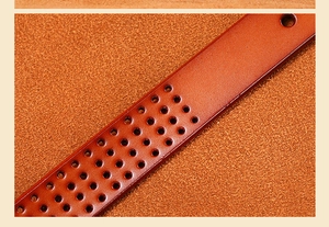 Macro detail of orange-brown leather belt featuring geometric perforated design and gloss