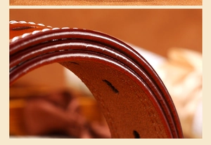 Macro detail showing brown leather belt with white stitching and refined edge painting