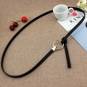 Fine ceinture noire minimaliste pour femme avec boucle dorée sur fond texturé