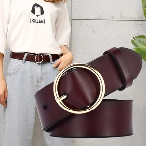 Women's dark red leather belt with round gold buckle on light blue jeans