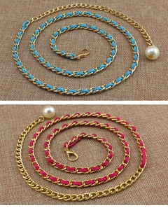 Dettaglio di cinture a catena in metallo intrecciato rosa e blu con ciondoli perla