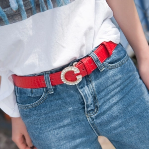 Red faux crocodile PU belt with rhinestone G-buckle worn on blue denim jeans