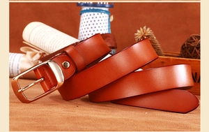 Detail of a brown leather belt with a classic gold pin buckle on a vintage background