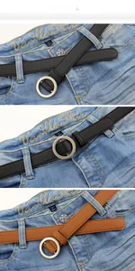 Détail de ceintures fines en cuir noir et marron avec boucles rondes sur un jean bleu
