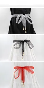 Détail de ceintures en mousseline blanche, noire et rouge avec d'élégants pendentifs perles