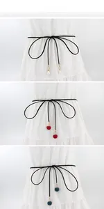 Detail der dünnen schwarzen Taillenkordel mit Perlen- und Webball-Anhängern auf weißem Kleid