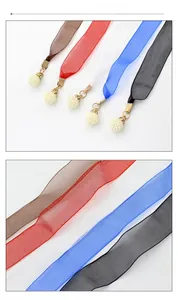 Détail de ceintures en ruban de mousseline coloré avec pendentifs en perles et métal doré