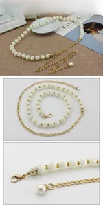 Détail de la ceinture chaîne en métal doré avec perles blanches et fermoir homard