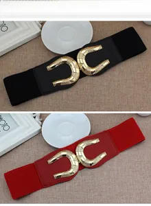 Detail view of wide elastic waist belts in black and red with metal horseshoe buckles