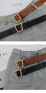 Detail view of the matte gold trapezoid buckle on black and brown leather belts