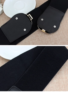 Detail of black wide elastic belt showing golden buckle screw and dense fabric texture