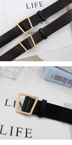 Close-up of geometric gold trapezoid buckle on black and brown leather waist belts
