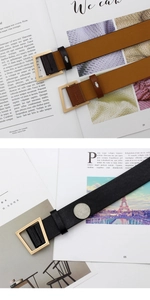 Detail of classic black and brown leather belts with gold geometric buckles on high-end texture