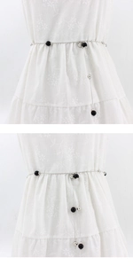 Detail of silver metal waist chain with black and silver beads on a white dress