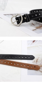Détail de la boucle argentée en cœur et des motifs ajourés sur ceintures noir et marron