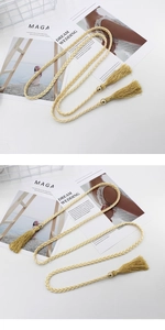 Dettaglio della cintura intrecciata in corda beige con eleganti nappe e perline oro