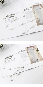 Detail of elegant layered silver chain with white pearls and polished metal beads