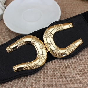 Women's wide elastic corset belt with double golden U-shaped buckles on a brown surface