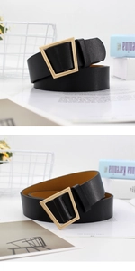 Detail of a wide black leather belt featuring a polished gold trapezoid metal buckle