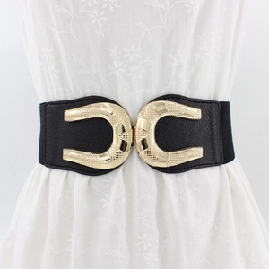 Women's wide elastic waist belt with textured gold U-shaped metal buckle on floral dress