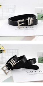 Close-up detail of black textured leather belt with three decorative silver metal pin buckles