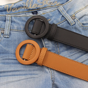 Women's minimalist leather belts with round buckles in black and brown over denim pants