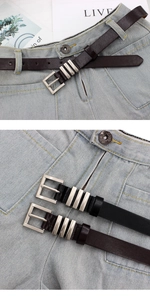 Detail of slim black and brown belts with silver rectangular buckles on jeans