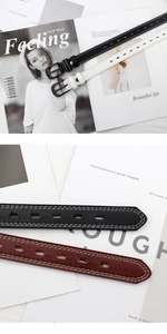 Detailed view of slim leather belts in black white and brown with contrast stitching