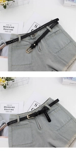 Detail of slim black leather belt with golden buckle on high-waist denim shorts