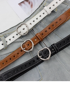 Trois ceintures en cuir avec boucles coeur argentées en noir, blanc et marron sur denim