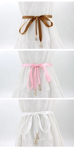 Detailansicht von Satin-Taillenbändern mit Goldanhängern in Braun, Rosa und Weiß