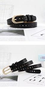 Detail of slim black leather belt featuring a golden horseshoe buckle and perforated design