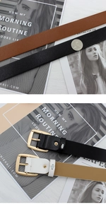 Close-up of four colors of faux leather belts with square gold buckles on fashion magazines