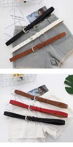 Detailed view of multiple slim leather belts in black and red on denim shorts