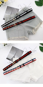 Détail de ceintures en toile rayée avec boucles rondes dorées sur shorts en jean