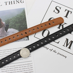 Minimalist leather belts in black and brown with circular pin holes and coin for size scale