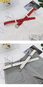 Detail of red and white thin faux leather belts with silver buckles and decorative eyelets