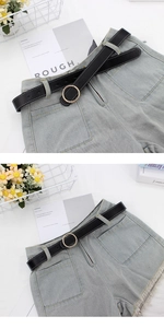 Détail d'un short en jean bleu clair avec bords effilochés et ceinture noire à boucle dorée