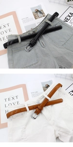 Detail of slim black and brown faux leather belts with silver buckles on denim shorts