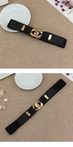 Detail of a women's black elastic belt featuring a golden interlocking ring buckle